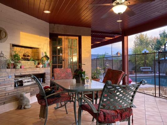 A cozy patio dining area with a table and chairs overlooking a pool.