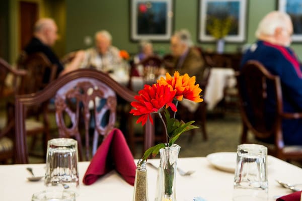 Dining room with flower centerpiece and residents socializing