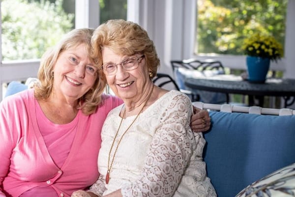 Two women smiling together in a cozy lounge area