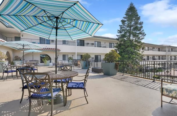 Patio with tables, chairs, and striped umbrellas at Huntington Terrace