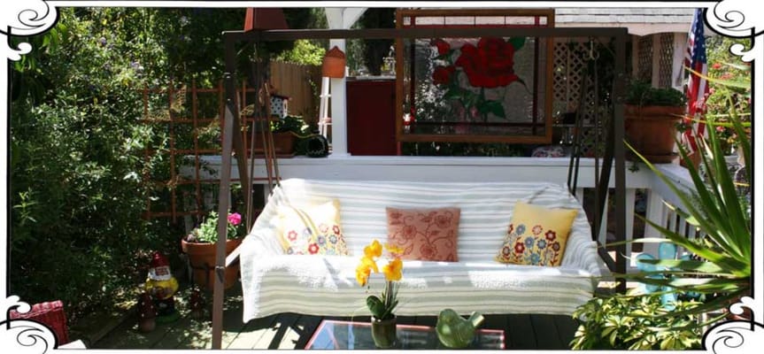 A garden swing with colorful cushions and flowers in a cozy setting.