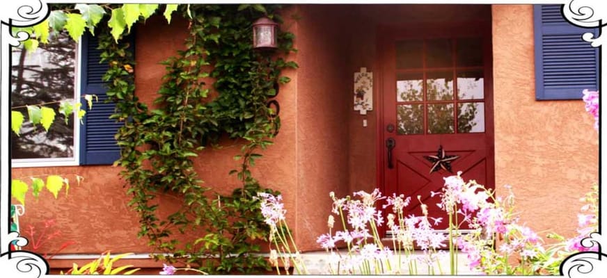 Entrance with a red door and flowers at Lucie's Cozy Cottage