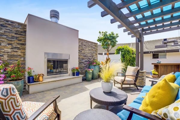 A stylish outdoor patio with a fireplace, seating, and colorful plants.