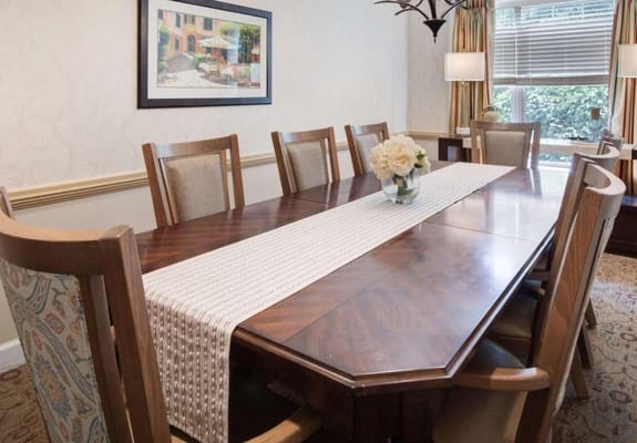 A dining room setup with a large wooden table and floral centerpiece