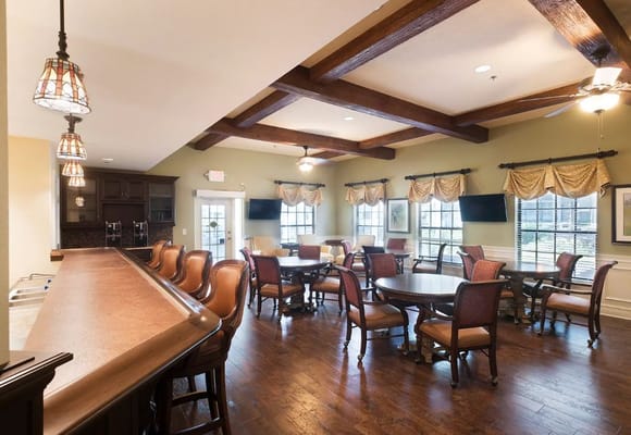 Spacious common area with tables, chairs, and a bar in Regency Elderly Care