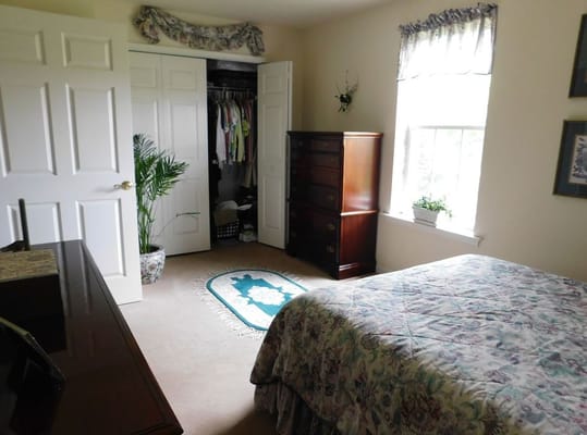 Bright bedroom with a bed, dresser, and closet.