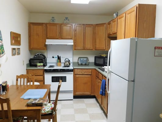 A bright kitchen with wooden cabinets and white appliances.