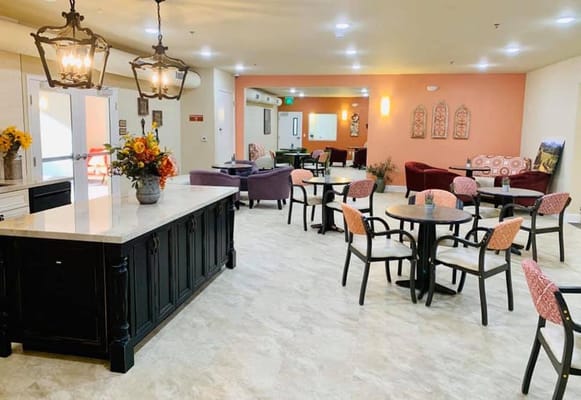 Bright and inviting common area with tables and chairs, floral arrangements, and cozy seating.