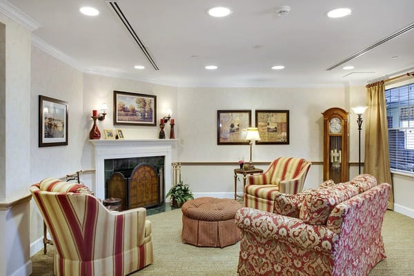 Comfortable seating area with floral and striped chairs, a fireplace, and decorative artwork.