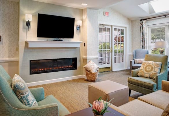 A cozy living room with a fireplace, comfortable seating, and a large TV.