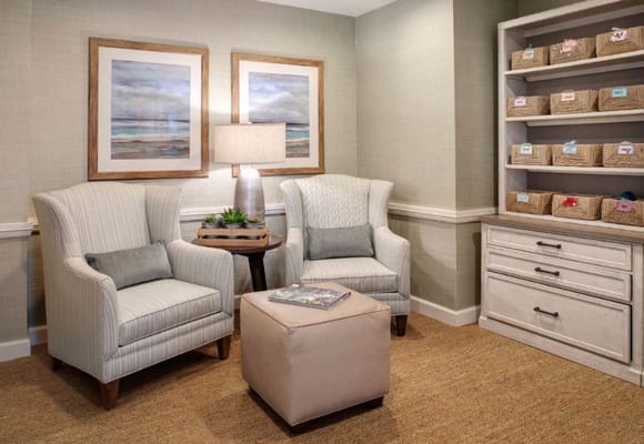 A cozy living room with two armchairs, a lamp, and a bookshelf of baskets.