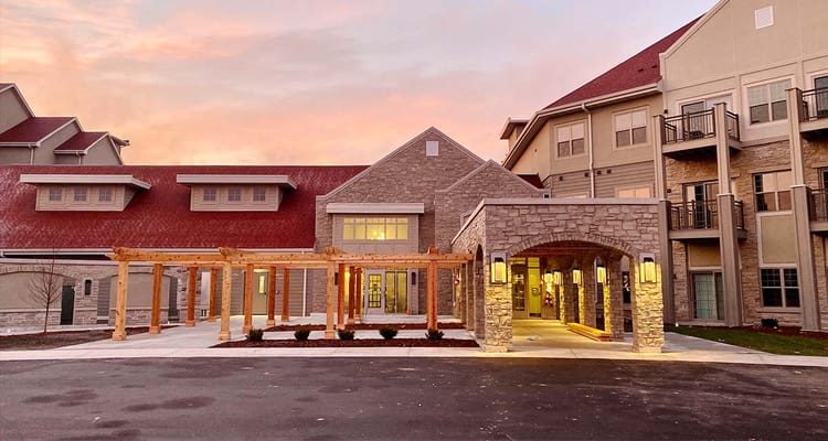 The front entrance of Trinity Woods senior living facility illuminated at sunset.