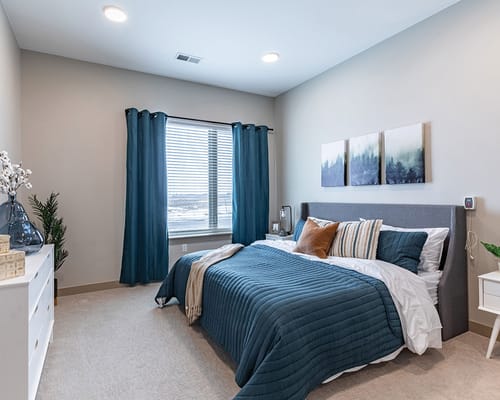 Stylish bedroom with a bed, artwork, and large window.