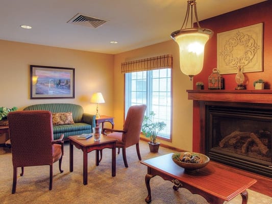 A cozy living room with a green couch, two chairs, a coffee table, and a fireplace.
