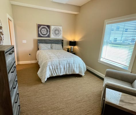 Comfortable bedroom with a bed, dresser, and armchair