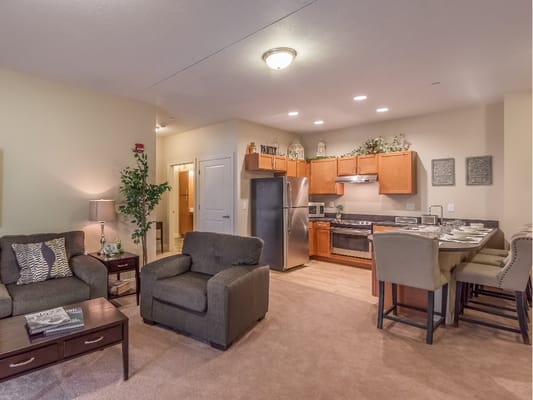 Living room with seating area and kitchen in apartment at The Heritage at Legacy
