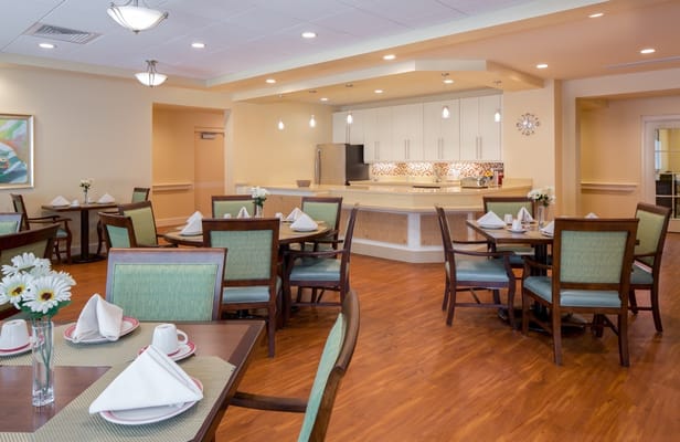 Well-set dining room with tables and a kitchen in the background.