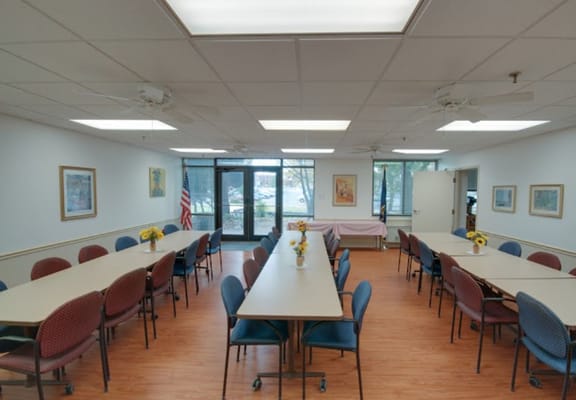 A spacious dining room with tables and chairs, featuring flower centerpieces