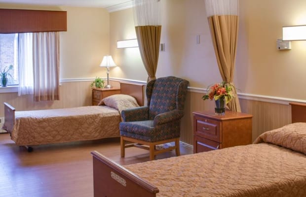 Cozy shared bedroom with two beds, a chair, and a window in Village Green of Bristol.