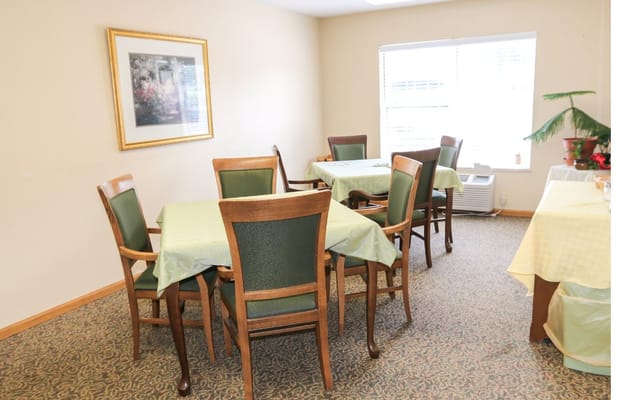 Cozy dining area with green tablecloths and wooden chairs