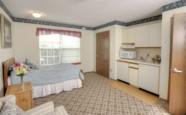 Interior of a cozy resident room with a bed and kitchenette