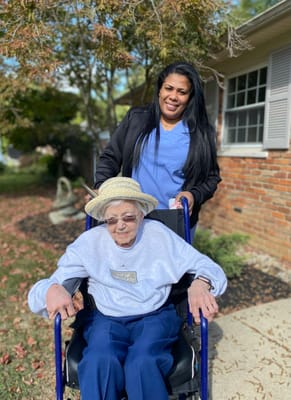 A staff member assisting an elderly resident outdoors