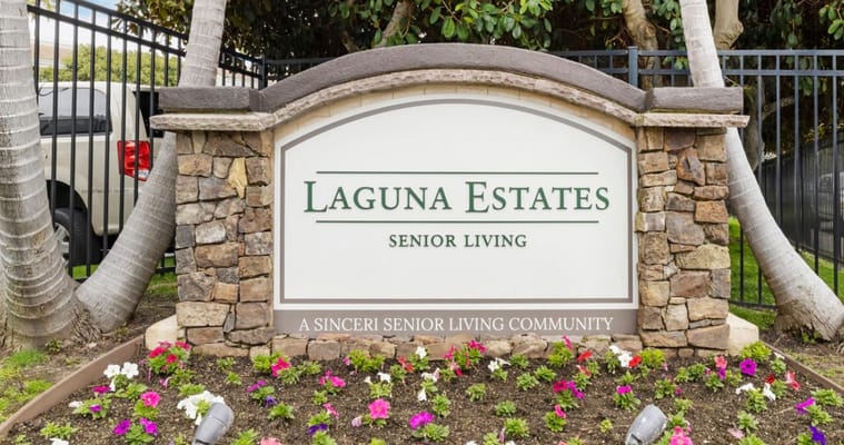 Sign for Laguna Estates Senior Living with flowers in front