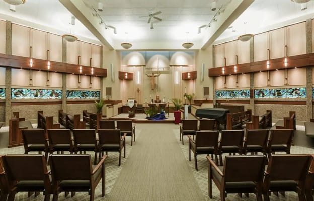 Interior view of the chapel with wooden chairs and stained glass