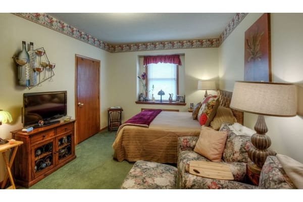 A cozy bedroom featuring a bed, a TV, and floral decor.