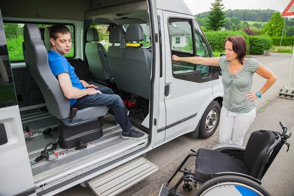 Staff assisting a resident with a wheelchair van