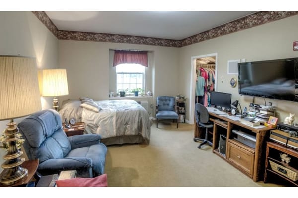 A well-furnished bedroom with a bed, seating area, and a desk.
