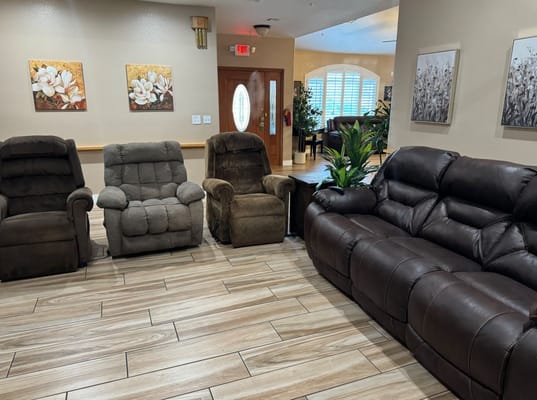 A cozy lounge area with four recliners and decorative art on the walls.