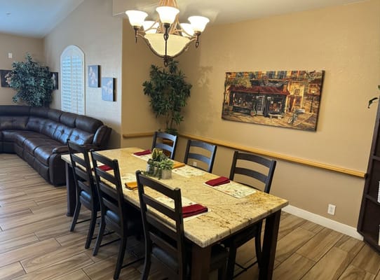 Dining table set in a cozy area with a leather couch and artwork