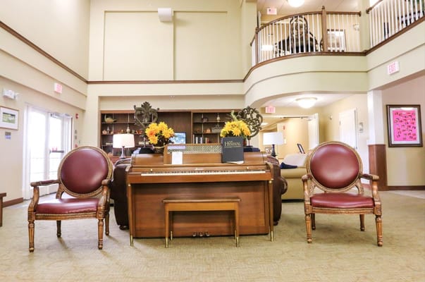 A living room with a piano and elegant chairs at Vintage Park.