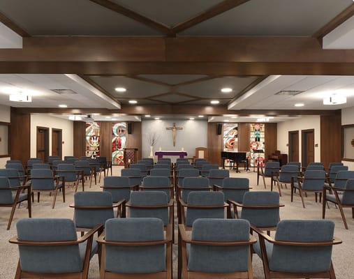Interior view of the chapel featuring rows of chairs, a cross, and stained glass windows