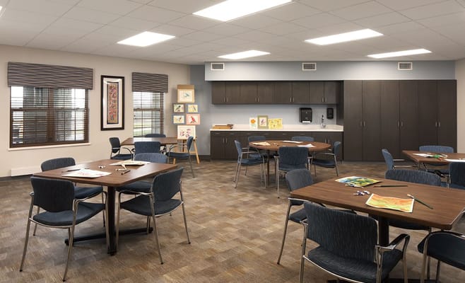 Art room with tables and chairs, featuring artwork displays