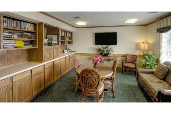 Cozy common area with a round table, chairs, and bookshelves.