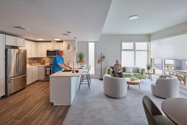 Bright interior of a spacious common area with staff and resident