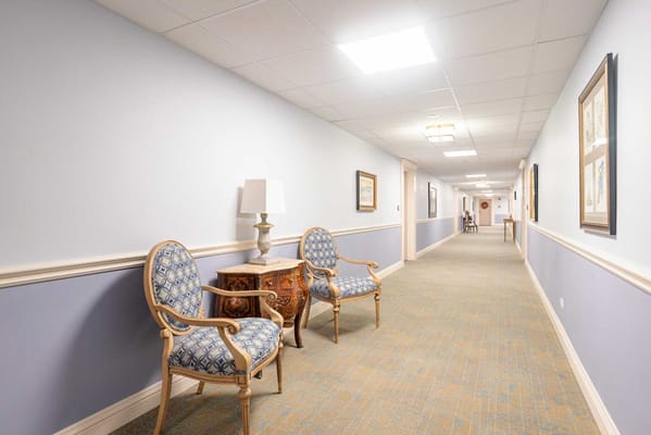 A hallway with chairs and decorative elements in a senior living facility