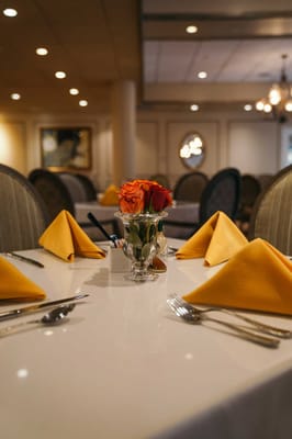 Dining table set with orange napkins and flowers