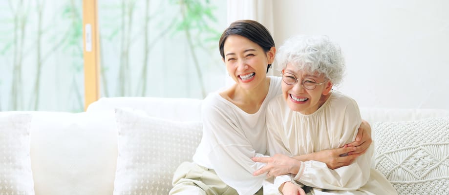 Two women smiling and embracing on a couch