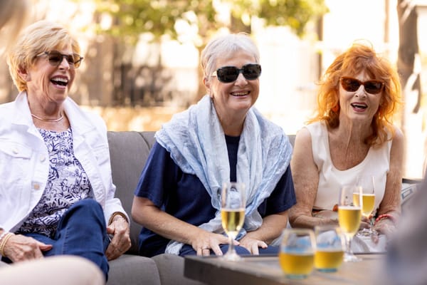 Three smiling residents enjoying drinks outside