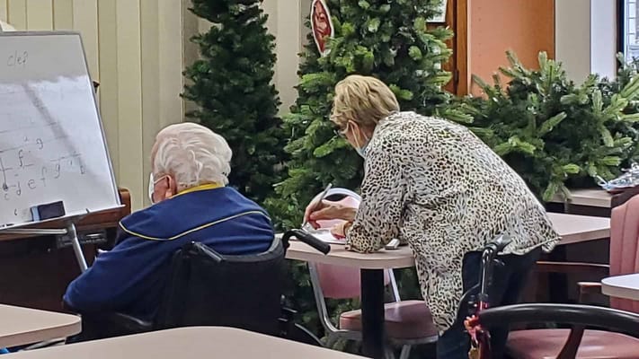 A staff member assisting a resident in an activity room
