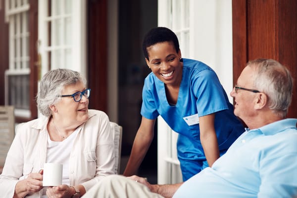 A caregiver interacting with two residents outdoors