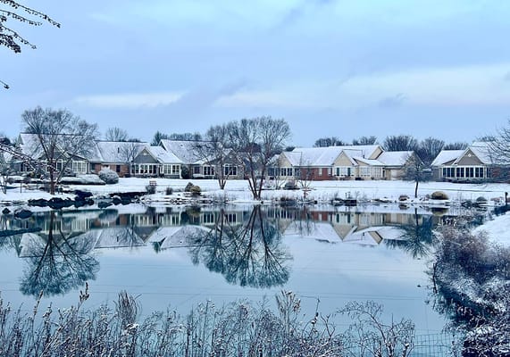 Exterior view of a senior living facility by a pond in winter