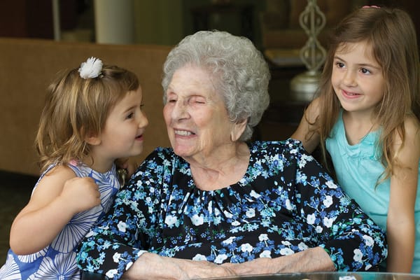 Elderly woman smiling with two young girls