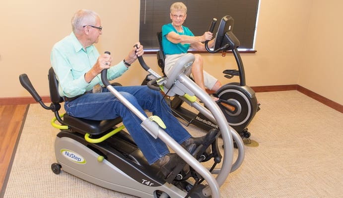 Residents using exercise equipment in a gym