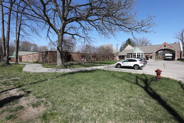Exterior view of Manoogian Manor with trees and parking