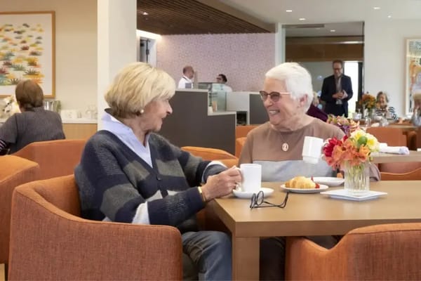 Two residents chatting over coffee in a dining area