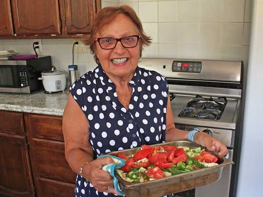 Senior resident smiling while preparing a meal in the kitchen